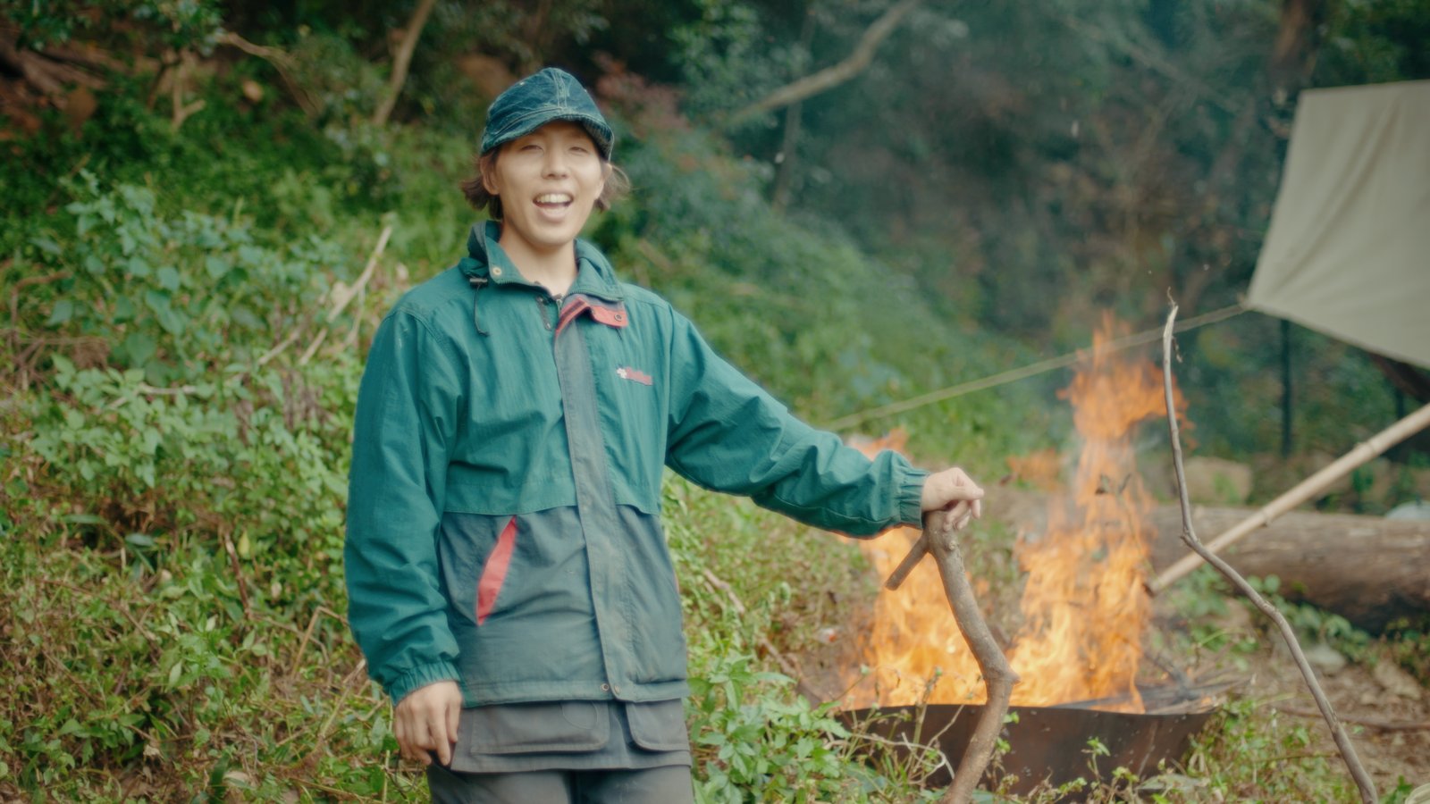 里山の焚き火のそばで笑うながさわかんた